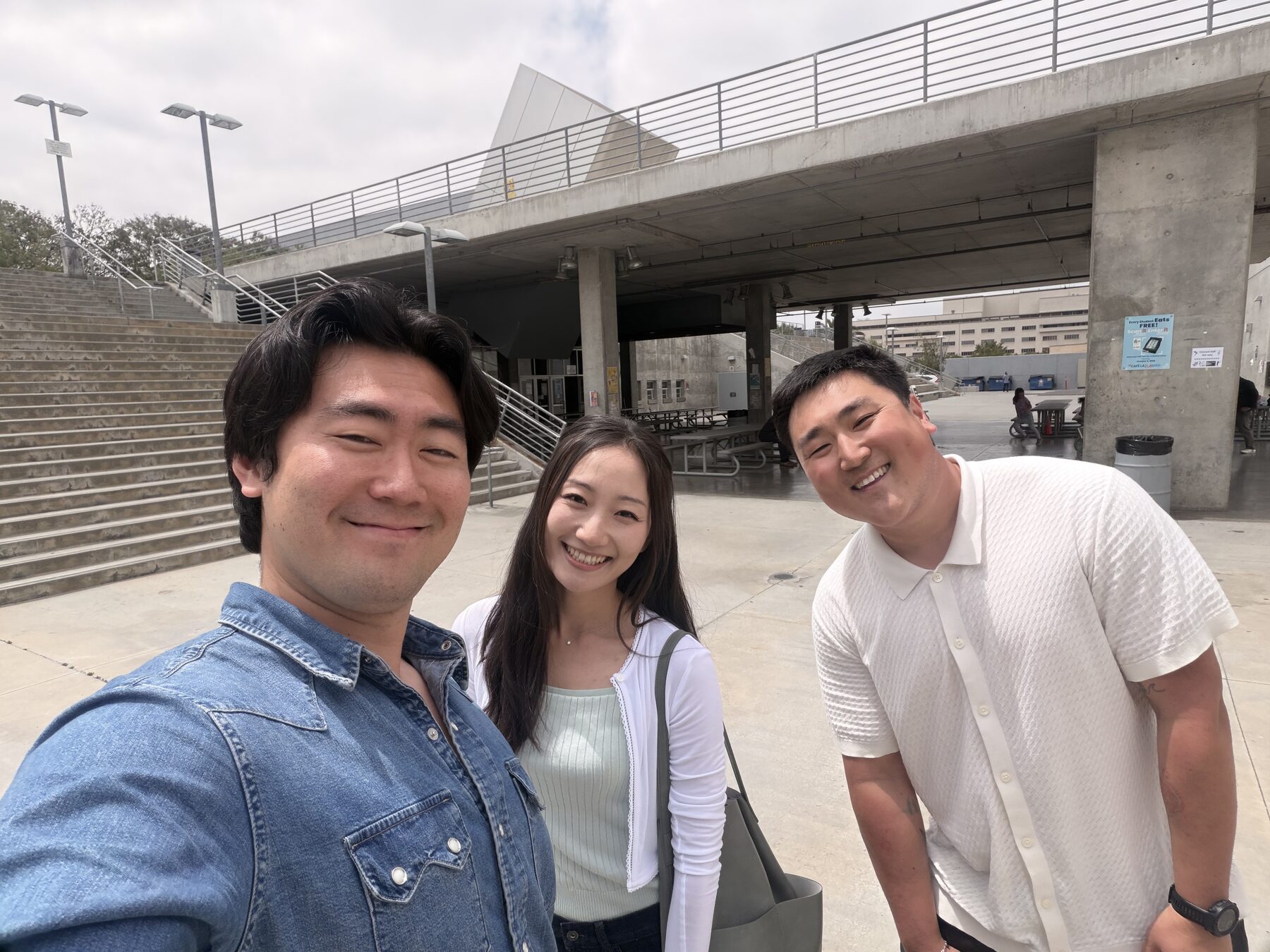 Selfie with Minyoung and Justin in the courtyard outside Citizens Church — concrete overpass behind us, overcast sky. Crystal and Josh had already left.